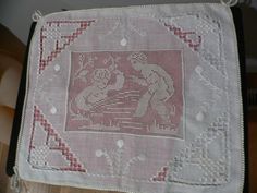 a piece of cloth hanging from a hook on a wooden floor with an embroidered design