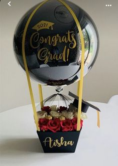 a graduation balloon with flowers in it sitting on top of a table