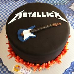 a black cake with an electric guitar and nameplate on the top that says metallic