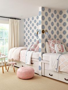 a bedroom with two twin beds and pink stools in front of the bed, next to a window