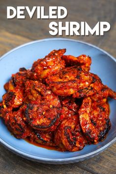 a blue bowl filled with cooked shrimp on top of a wooden table and text overlay that reads, deviled shrimp