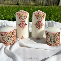 three candles sitting on top of a white cloth