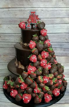 a three tiered chocolate cake with strawberries on the bottom and letters at the top