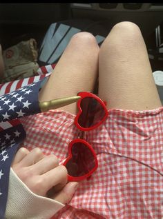 a woman laying on top of a bed wearing red sunglasses and an american flag scarf