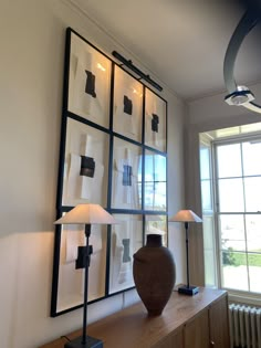 a large vase sitting on top of a wooden table next to a wall mounted art piece