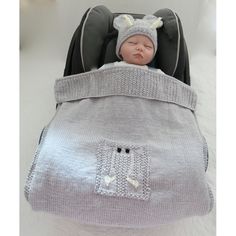 a baby sleeping in a stroller with a knitted hat on it's head