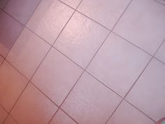 a person standing in front of a white tiled bathroom floor with urinal and trash can