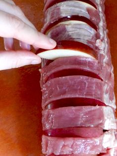 a person is placing slices of meat on top of each other