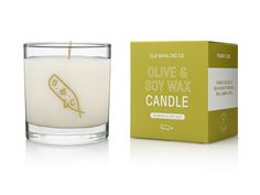 an olive and soy wax candle next to a box