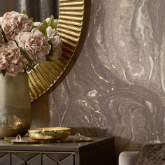 a vase filled with pink flowers sitting on top of a table next to a mirror