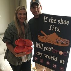 a man and woman standing next to each other with shoes on their feet in front of a sign that says if the shoe fits, will you croc my world at prom