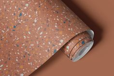 an orange wallpaper with blue and brown speckles on the top, next to a roll of tape