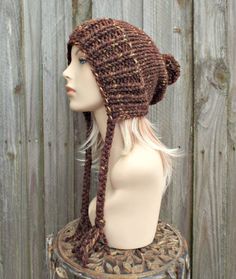 "Style: Chunky knit beanie with pom pom and braided ties, for men or women. Color: This sample hat is shown in Sequoia, a mix of browns, golds and rust. Sizes: One size fits average teen or adult head size of 20\" to 23\" (50.5 cm to 58 cm). Fiber Content: 80% acrylic, 20% Wool Characteristics: Chunky, very soft, warm and cozy. Care Instructions: Hand wash, dry flat. Every item from Pixiebell is handmade and knit or crocheted to order, unless otherwise stated in title of the item as \"ready to s Knitted Brown Yarn Bonnet, Brown Yarn Bonnet Hat, Brown Outdoor Crochet Hat, Brown Handmade Crochet Hat For Outdoor, Brown Chunky Knit Yarn Hat, Brown Hand Knitted Hat In Acrylic Yarn, Knitted Brown Acrylic Yarn Hats, Hand-knitted Brown Hat In Acrylic Yarn, Cozy Brown Crochet Hat In Acrylic Yarn