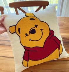 a winnie the pooh pillow sitting on top of a wooden chair