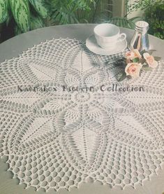 an old crochet doily is sitting on a table next to a cup and saucer