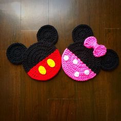 two crocheted mickey and minnie mouse hats on top of a wooden floor,