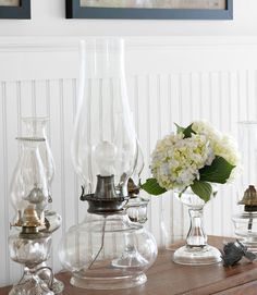 vases with flowers and other items sit on a table in front of two framed pictures