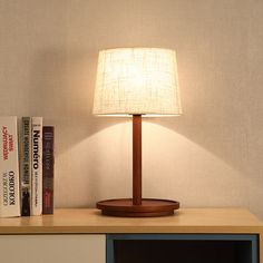 a lamp sitting on top of a wooden table next to a book shelf with books