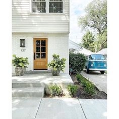 a blue van is parked in front of a white house with yellow door and windows