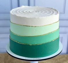 a green and white cake with gold stripes