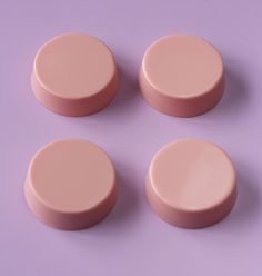 four pink pill caps sitting on top of a purple surface