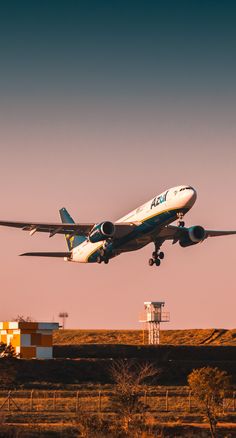 an airplane is taking off from the runway at sunset or dawn with its landing gear down