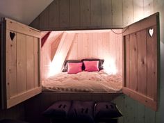 a bed in the corner of a room with two pillows on it and some lights