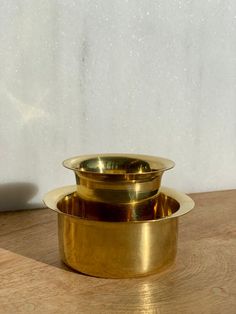 two golden bowls sitting on top of a wooden table