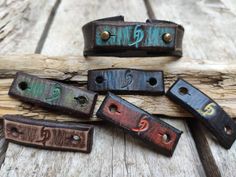 four leather bracelets with numbers on them sitting on a piece of driftwood next to each other