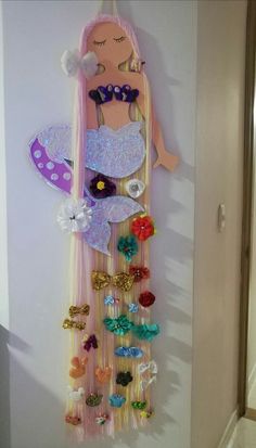 a barbie doll hanging from the side of a wall with hair clips attached to it