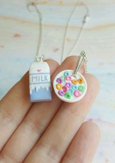 a hand holding a small necklace with buttons on it and a milk bottle in the background