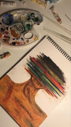 an art project with paints and brushes on the table next to it is a drawing of a woman's head