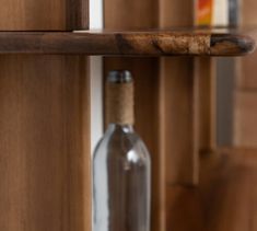 an empty bottle sitting on top of a wooden shelf next to a corked door handle