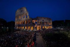 an aerial view of the colossion at night, with people standing around it