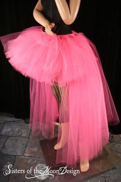 a woman wearing a pink tulle skirt and black top with her hands on her hips