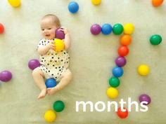 a baby sitting on the floor surrounded by balloons and balls with the words months spelled out