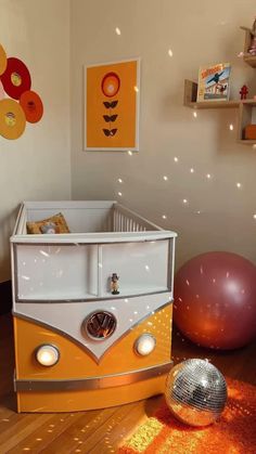 a baby's room with an orange and white bus crib next to a ball