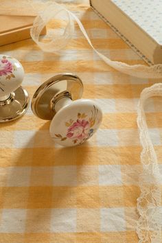 two door knobs sitting on top of a yellow and white checkered table cloth