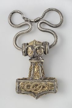 an antique silver and gold necklace with a large metal object hanging from it's side