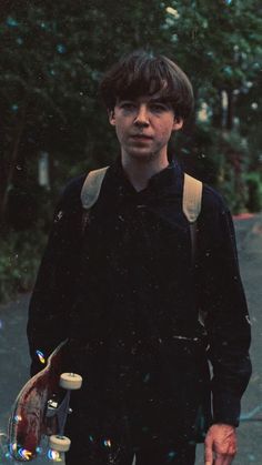 a young man holding a skateboard in his hand