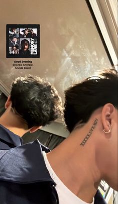 the back of a woman's head with tattoos on it and behind her is an image of two men