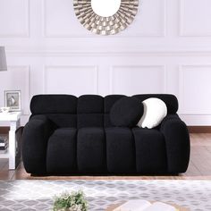 a living room with a black couch and white pillows