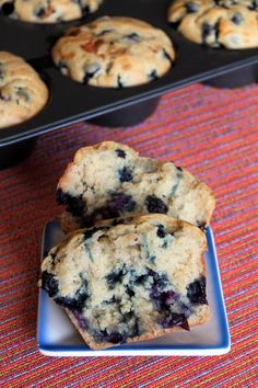 two blueberry muffins on a plate next to some muffin tins