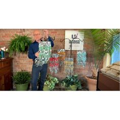 a man standing in front of a display of vases and potted plants on a brick wall