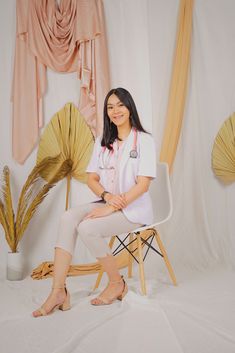 a woman is sitting on a chair in front of some drapes and palm trees