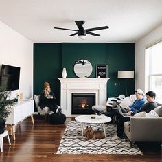 two people sitting on couches in front of a fireplace with a dog laying on the floor