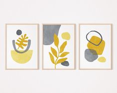 three yellow and gray art prints hanging on a wall