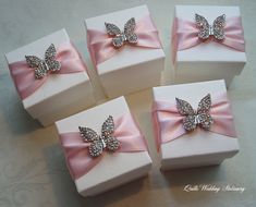 four white boxes with pink bows and diapered butterflies on them are sitting on a table