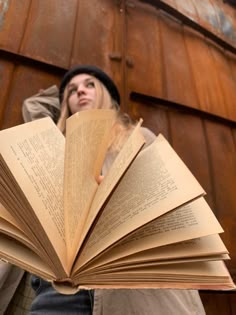 a woman holding an open book in front of her face