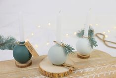 three candles are sitting on top of a piece of wood and decorated with pine branches